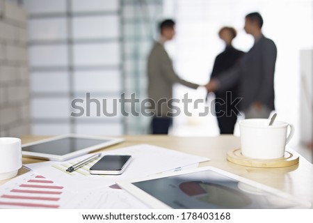 close-up of business items with people meeting in background.