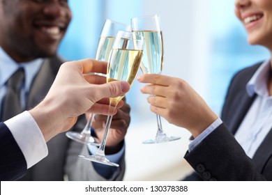 Close-up of business partners hands cheering up with flutes of golden champagne