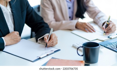 Close-up of business people taking note at a meeting on clipboard for drafting, writing meeting minutes in office and printing on computer. - Shutterstock ID 2203706735