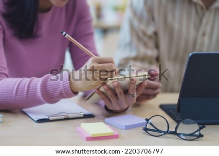 Close-up of business people taking note at a meeting on clipboard for drafting, writing meeting minutes in office and printing on computer.