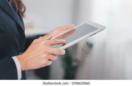 Close-up of business woman using tablet computer in the office. Female working on touching screen. Casual Asian woman. - Powered by Shutterstock