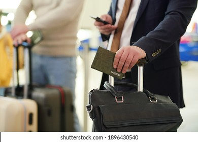 Close-up of businessman with bag and documents using his mobile phone while waiting for departure - Powered by Shutterstock