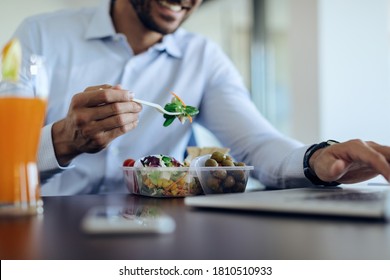 Close-up of businessman eating healthy food while using computer on lunch break in the office. - Shutterstock ID 1810510933