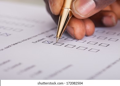 Close-up Of Businessman Filling Customer Survey Form