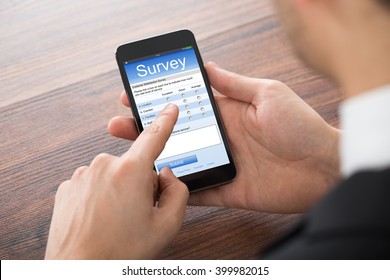 Close-up Of Businessman Filling Online Survey On Mobile Phone