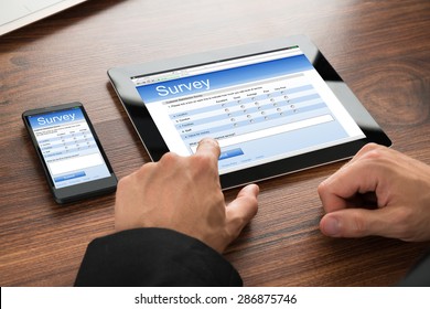 Close-up Of A Businessman Filling Survey Form Online On Digital Tablet And Cellphone