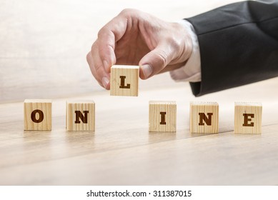 Closeup of businessman hand assembling word ONLINE with six wooden cubes with letters on them. Conceptual of internet, globalization and communication.
