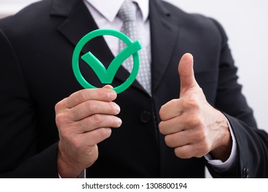 Close-up Of A Businessman Hand Holding Green Check Mark Icon