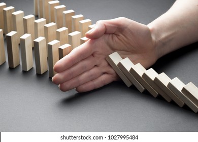 Close-up of a businessman hand stopping a falling domino effect of risk, crisis. - Shutterstock ID 1027995484
