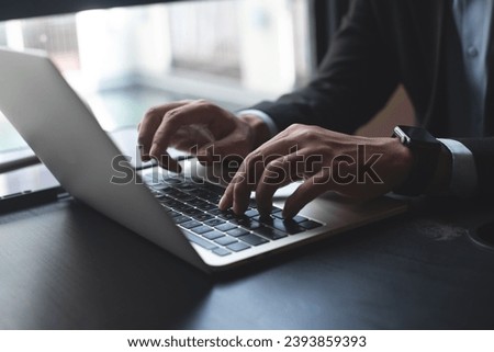 Closeup of businessman hand typing on laptop computer at office. Business man working on computer device, searching the information, surfing the internet on table at workplace