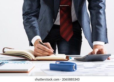 Close-up businessman hand writing to do list in diary at desk. Financial expertise and consulting. Manager in suit and tie planning day with personal organizer. Time management and work organization.