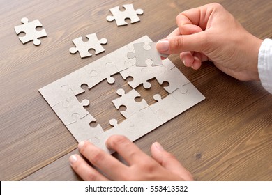 Close-up Of Businessman Hands Completing Jigsaw Puzzle - Powered by Shutterstock