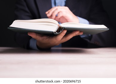 Closeup businessman holding a book over the desk and turn the page to search the information for reference - Shutterstock ID 2020696715