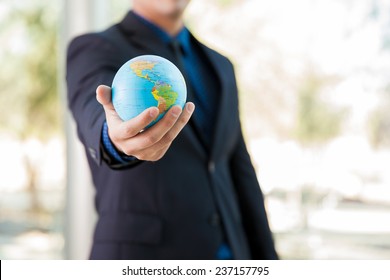 Closeup of a businessman holding a small globe in his hand