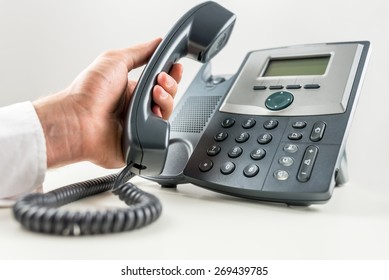 Closeup Of Businessman Holding A Telephone Receiver About To Make A Phone Call On Landline Telephone. Conceptual Of Customer Service Or Telemarketing.