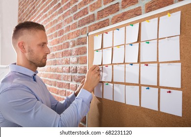 Close-up Of A Businessman Looking At Notes Attached On Bulletin Board