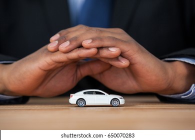 Close-up of businessman protecting toy car with hands - Powered by Shutterstock