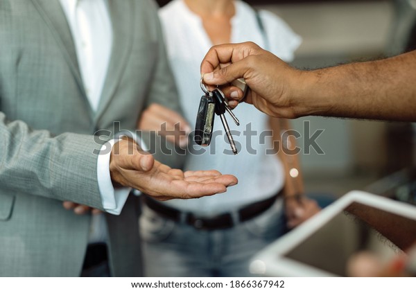 Close-up of businessman receiving car keys from a\
mechanic at auto repair shop.\
