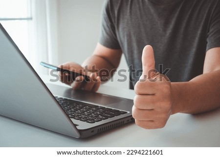 Close-up of businessman showing raised thumbs at the camera as a gesture of recommendation or good choice. Professional support and service team demonstrates satisfaction and gives a positive response