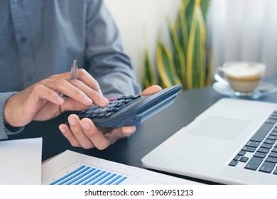 Close-up businessman using a calculator  to calculate the company's financial results On the wooden table in the office and business work background, tax, accounting, statistics and analyst