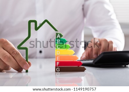 Close-up of a businessman using calculator holding outline of house model with energy efficiency rate