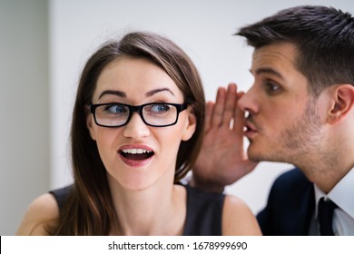 Close-up Of Businessman Whispering Into Female Partner's Ear
