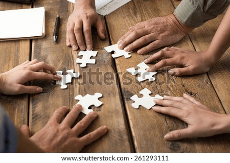 Closeup of businessman and woman with jigsaw puzzle pieces in office 