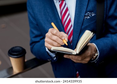 Close-up of businessman writing in diary outdoors - Powered by Shutterstock