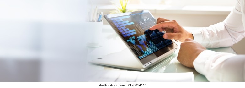 Close-up of a businessman's hand analyzing graph on laptop at workplace