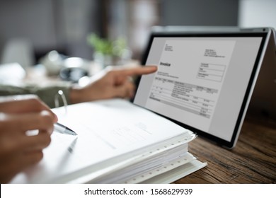 Close-up Of Businessman's Hands Working On Invoice On Laptop At Office