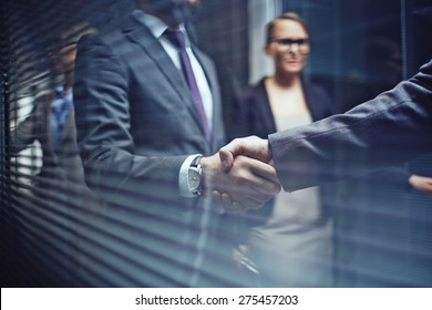 Close-up of businessmen handshaking on background of woman - Shutterstock ID 275457203