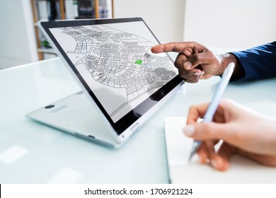 Close-up Of A Businesspeople Analyzing Cadastre Map On Computer In The Office