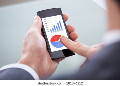 Close-up Of Businessperson Looking At Graph On Mobile Phone