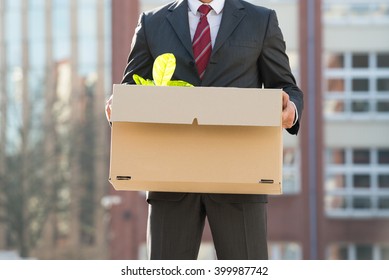 Close-up Of Businessperson Standing With Cardboard Box Outside Office