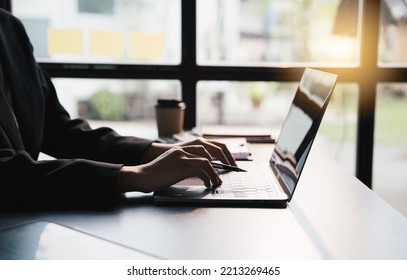 Close-up Businessperson Typing And Searching Data Internet On Laptop And Hands Holding Pen At Office Desk, Online Learning Concept.