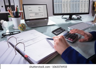 Close-up Of A Businessperson's Hand Calculating Invoice At Workplace - Shutterstock ID 1063376933