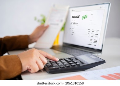 Close-up of a businessperson's hand calculating invoice at workplace, online taxes and invoice using computer and calculator