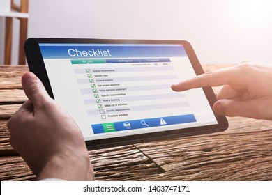 Close-up Of A Businessperson's Hand Filling Checklist Form On Digital Tablet