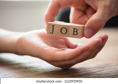 Close-up Of Businessperson's Hand Giving Wooden Block With Job Text To Candidate