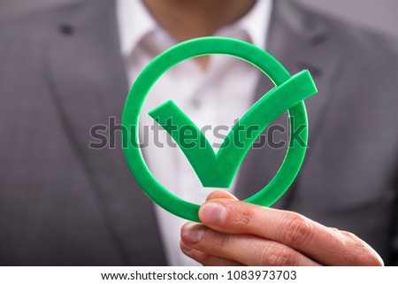 Close-up Of A Businessperson's Hand Holding Green Check Mark Icon