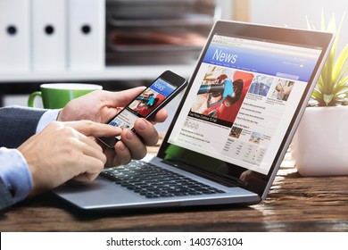 Close-up Of A Businessperson's Hand Holding Mobile Phone With Online News On Screen