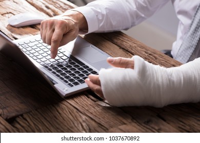 Close-up Of A Businessperson's Hand With Hand Injury Using Laptop
