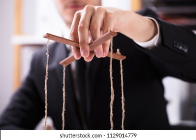 Close-up Of A Businessperson's Hand Manipulating Marionette With String