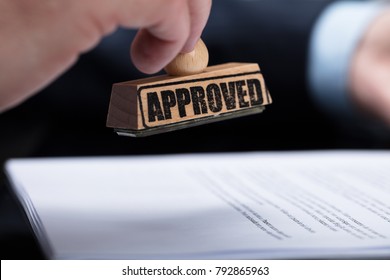 Close-up Of A Businessperson's Hand Stamping On Approved Contract Form