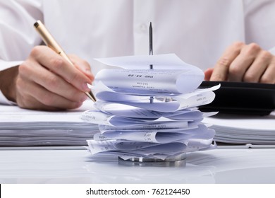 Close-up Of Businesswoman Calculating Tax At Office Desk