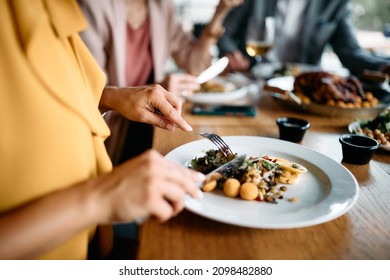 Close-up Of Businesswoman Eating While Having Lunch With Coworkers In A Restaurant. 