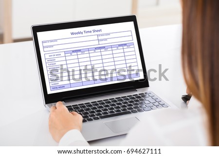 Close-up Of A Businesswoman Filling Weekly Time Sheet On Laptop In Office