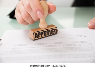 Close-up Of Businesswoman Hand Stamping Approved On Contract Paper
