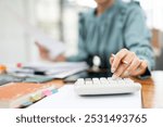 Close-up of businesswoman hands using a calculator to check company finances. Business woman calculating monthly expenses, managing budget, papers, loan documents, invoices.