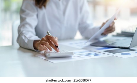 Close-up of businesswoman hands using a calculator to check company finances and earnings and budget. Business woman calculating monthly expenses, managing budget,  papers, loan documents, invoices.